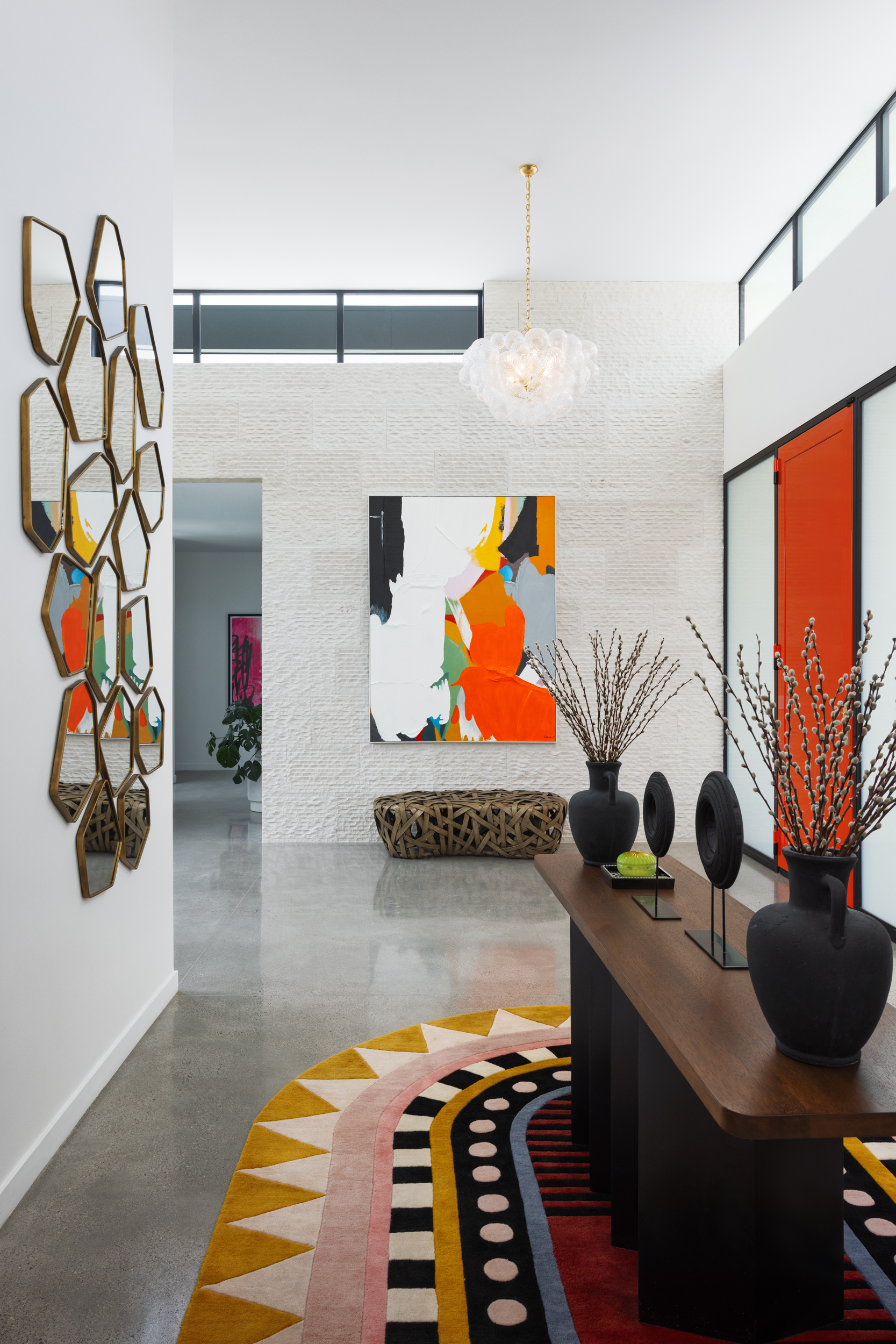 Entry with hexagonal mirror cluster, bold abstract art, and graphic rug