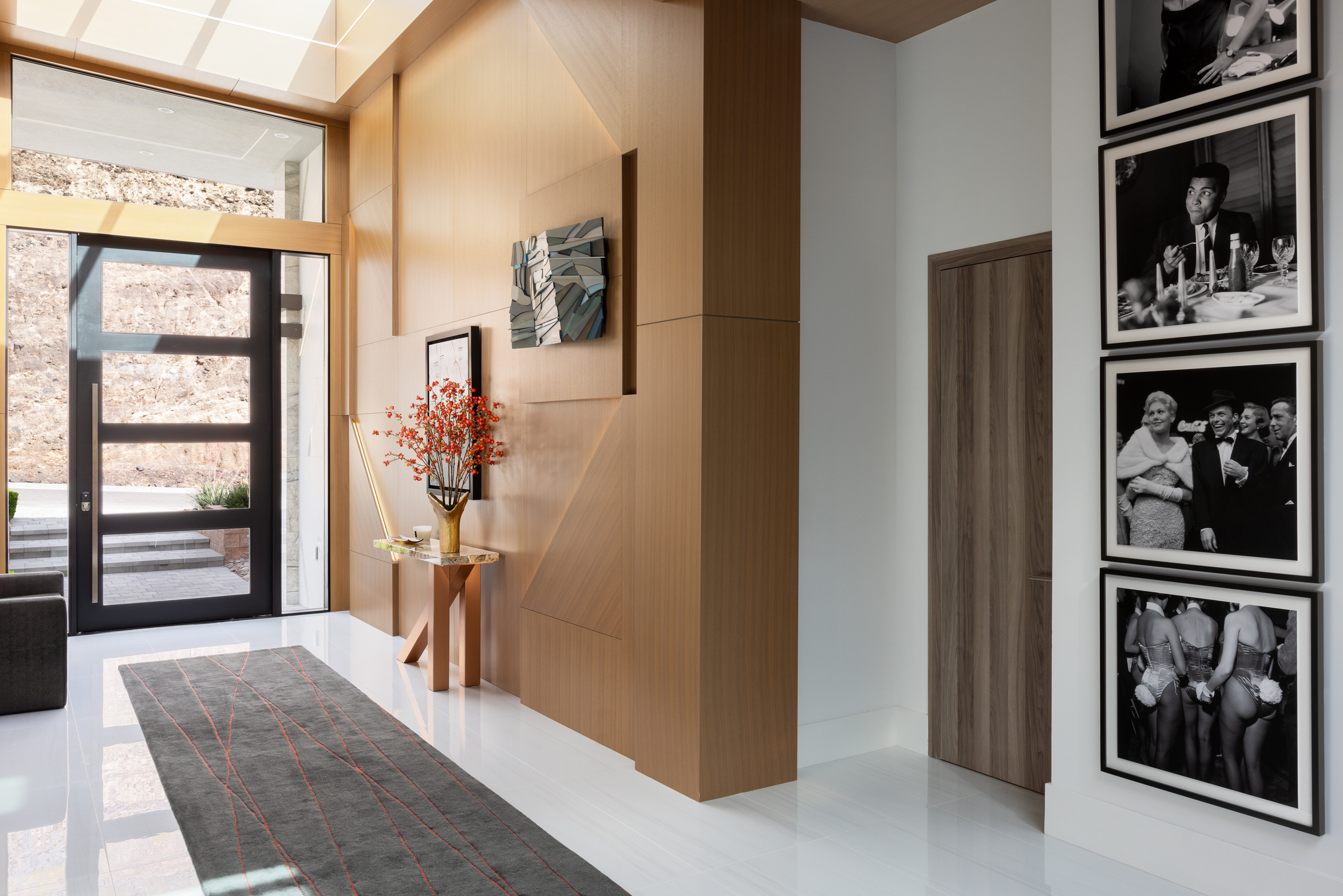 Entry hall with oak paneling, runner rug, and black-and-white photo gallery