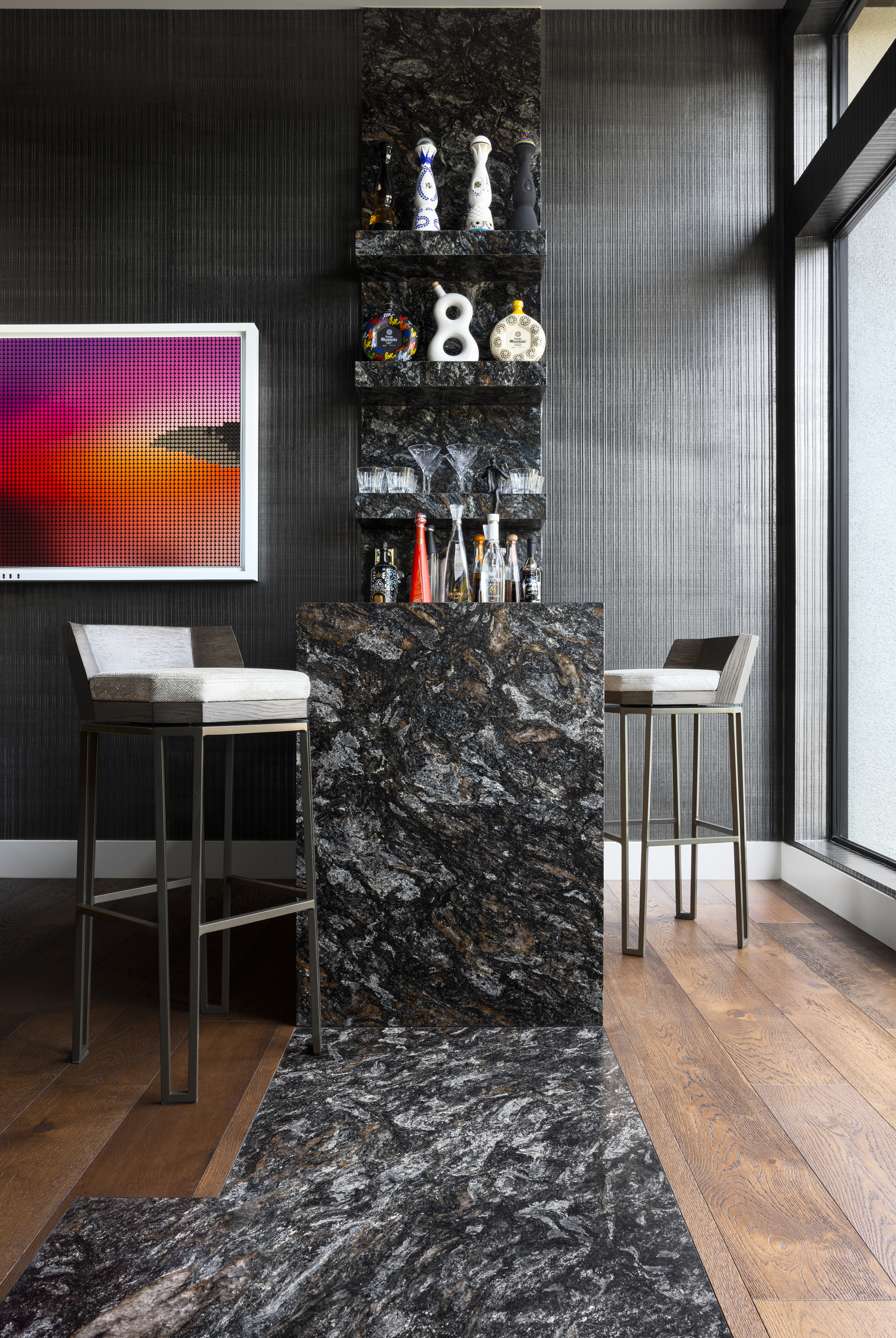 Dramatic black granite bar with upholstered stools and pixel sunset art