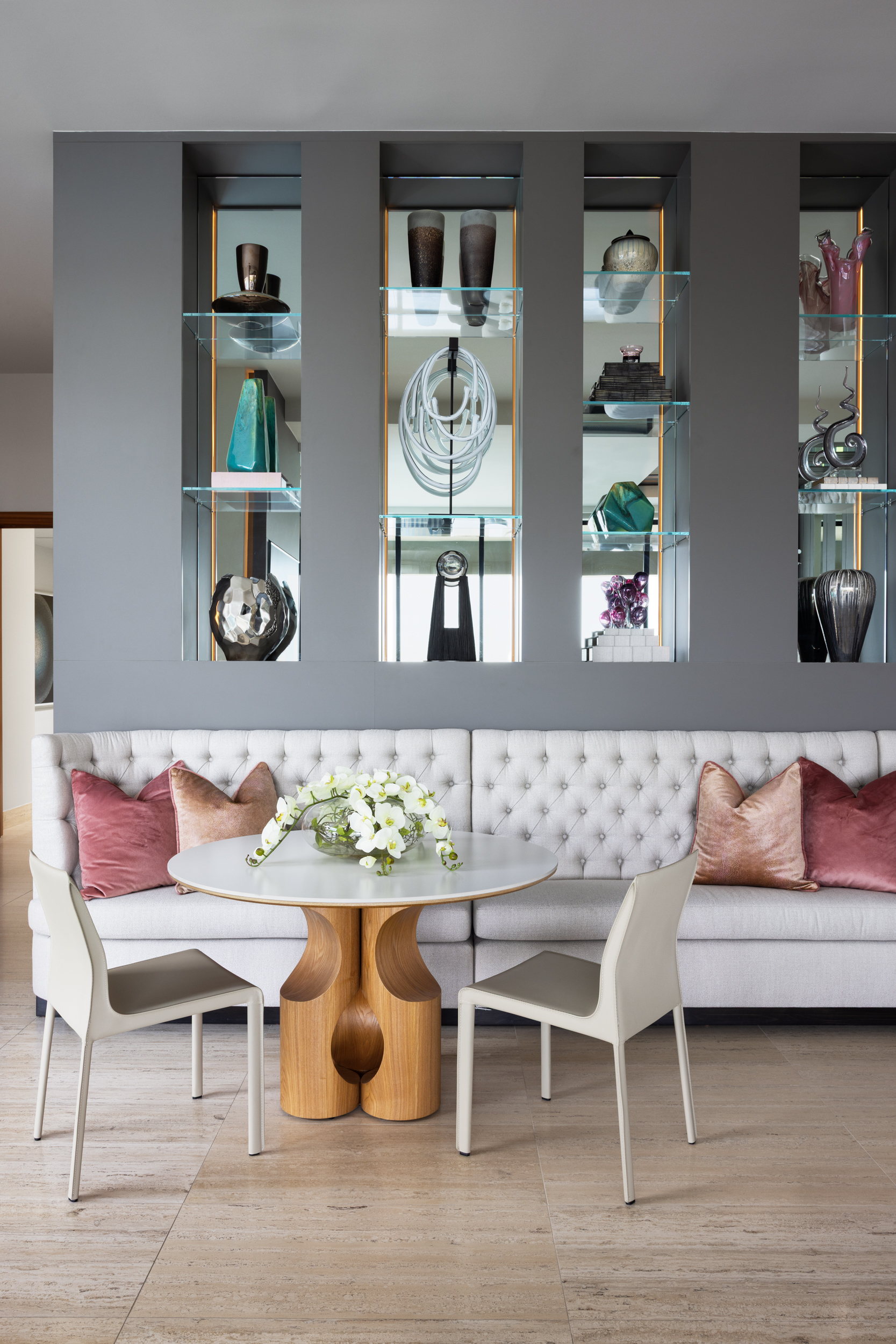Banquette dining nook with backlit display niches and sculptural wood table
