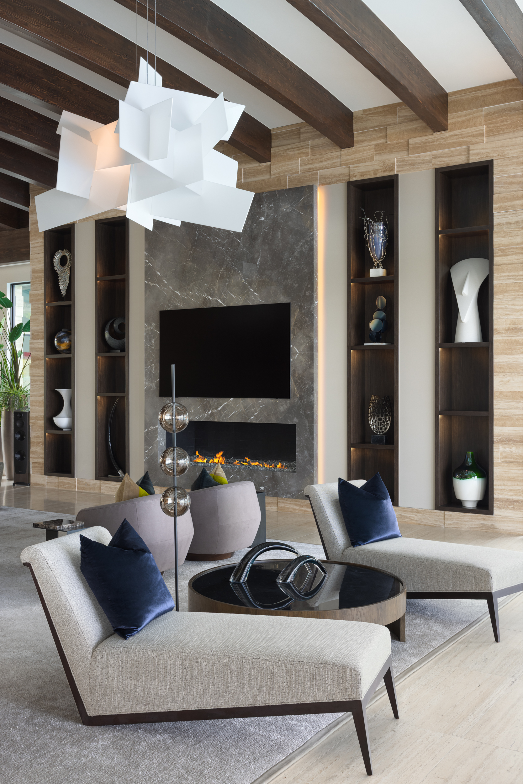 Living room with marble fireplace, sculptural white pendant, and beamed ceiling