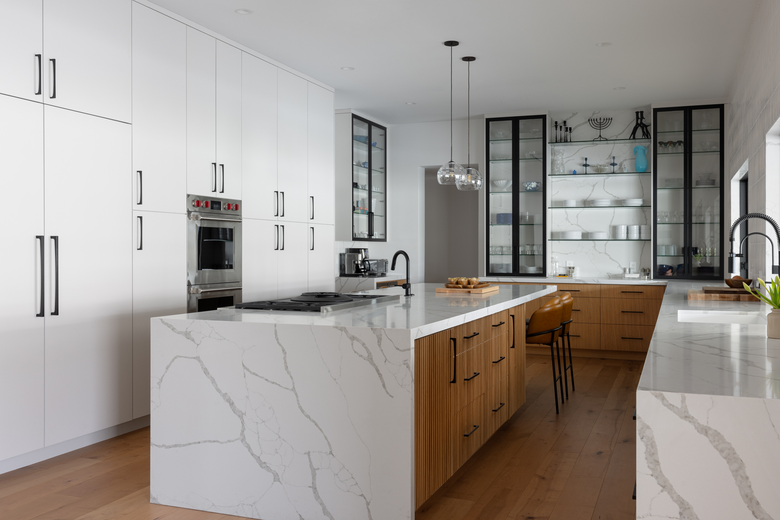 Modern white kitchen with waterfall quartz island and walnut cabinetry